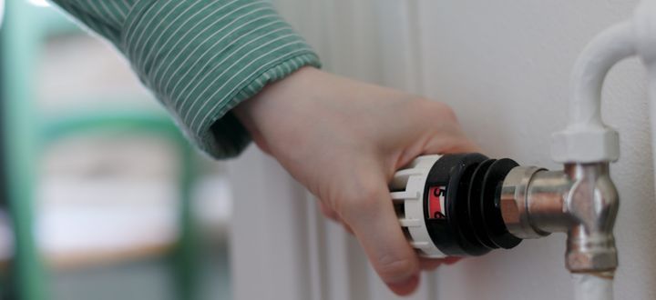 Hand vrider upp temperatur på termostat