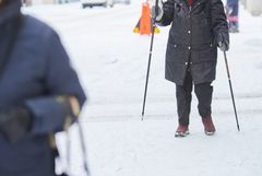 Person med gåstavar på vinterväglag