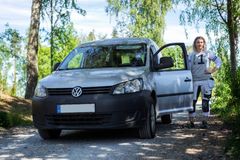 Kvinna i hantverkarkläder som står utanför en bil.