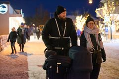 Familj som promenerar i mörkret med en barnvagn. De har reflexer.