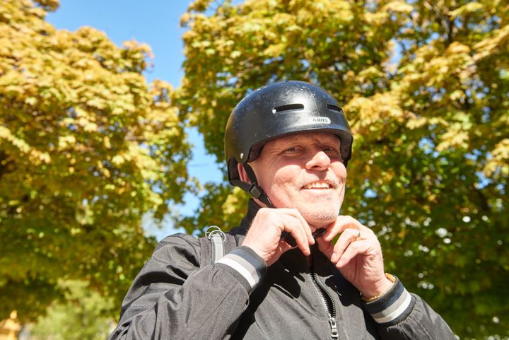 Vuxen man som knäpper en cykelhjälm.