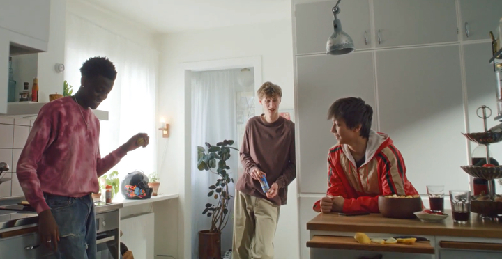 Skärmbild från kampanjfilmen "Låt inte tystnaden tala". Tre tonårskillar står i ett kök.