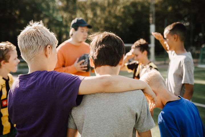 Idrottande pojkar står samlade runt en tränare. Foto: Stina Gränfors