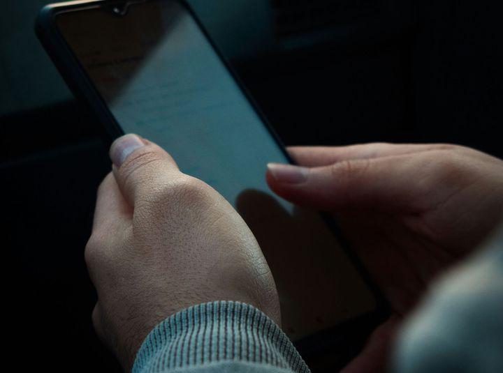 Kvinnohänder håller i en mobiltelefon.