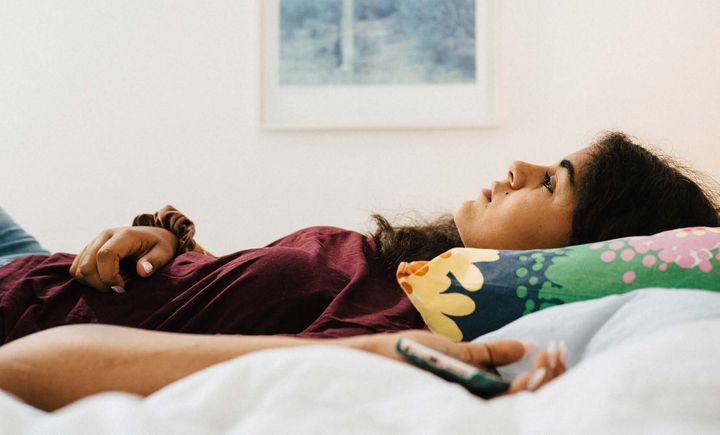 En ung kvinna ligger på sin säng. Foto: Stina Gränfors.