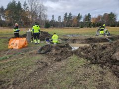 Flera personer i reflexkläder arbetar vid en uppsprängd grop.