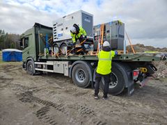 Lastbil med reservelsaggregat på flaket, förberett för transport vid krissituationer. Personen på bilden säkrar lasten.