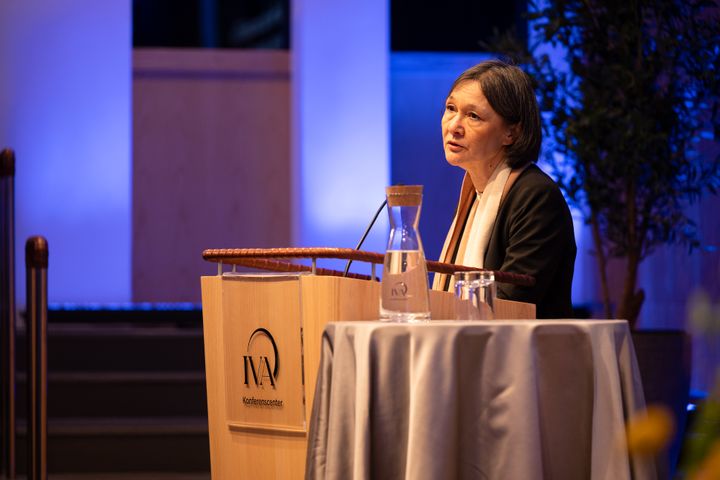 Sylvia Schwaag Serger håller ett tal vid ett podium märkt med IVA.