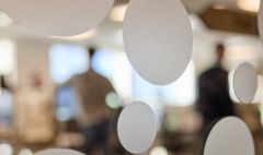 Personer står i suddig bakgrund bakom ett glas med vita cirklar.