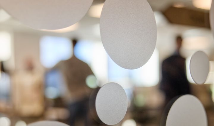 Abstrakt bild av cirkulära mönster på glas. Bakgrunden är suddig och visar personer i ett rum.