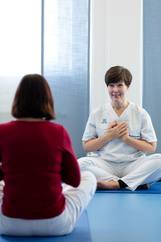 Två kvinnor som sitter mittemot varandra och gör en övning i mindfulness.