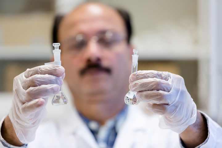 En forskare som håller upp två kärl.