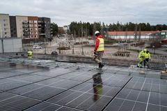 Byggarbetare arbetar med solcellspaneler på ett tak.