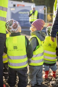 Förskolebarn med gula byggvästar på en byggarbetsplats