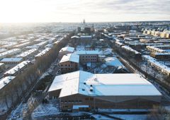 Flygfoto över snötäckt byggplats i Uppsala där en skola byggs.