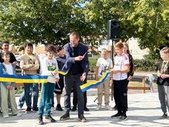 En grupp elever klipper invigningsband tillsammans med en vuxen man utomhus.