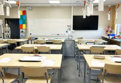 Klassrum med träbord och stolar, samt undervisningsmaterial på väggarna.