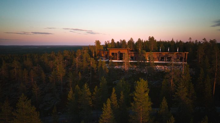 Flygfoto av lyxhotellet Octola Private Wilderness omgivet av skogvid solnedgång.