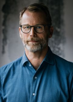 Joakim Ramsberg i blå skjorta framför en betongvägg.