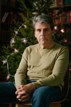 En person sitter framför en julgran med rosa ljus.