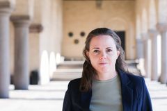 Alexandra Mattsson står i en mörk kavaj med stadshusets kolonner och valvbågar i bakgrunden.