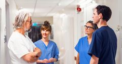 Sjuksköterskor och läkare i en sjukhuskorridor som samtalar.