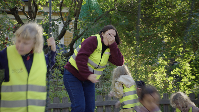 En förskolepedagog håller handen över munnen efter att ha blivit träffad av en gunga i ansiktet.