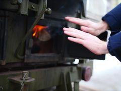 Händer värms vid en eldstad på en spis utomhus.