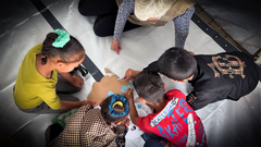 Barn målar på papper på golvet tillsammans med en vuxen.