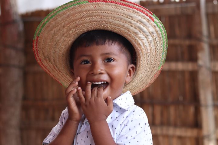 En ung colombiansk pojke med en stor stråhatt ler.