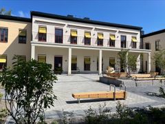 Hus med stenlagd gård och buskar och växter.