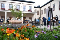 Blommor i en rabatt och många människor som minglar på innergården.