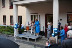 Två kvinnor vid ett blått invigningsband. De ler. En av dem står med en guldig sax.