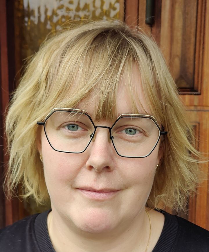 Blond kvinna med kort hår och tunna svartbågade glasögon