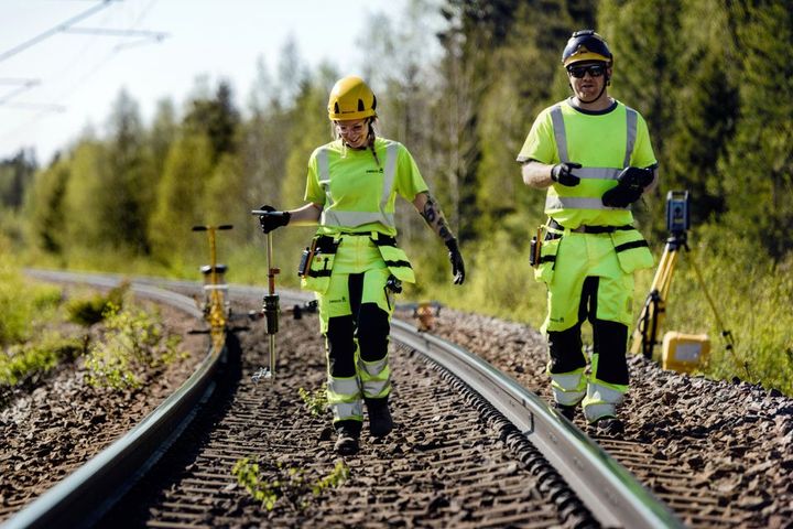 Två Swecoanställda går längst ett tågspår med mätinstrument i handen.