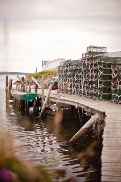Lobster traps and a boat hang off a small pier near the main harbour in Sambro, Nova Scotia, Canada
