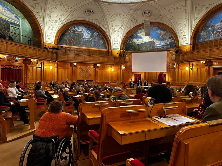 Bilden visar publiken som deltar vid ett riksdagsseminarium i Andrakammarsalen i Östra riksdagshuset. Längst fram finns scenen med talarna.