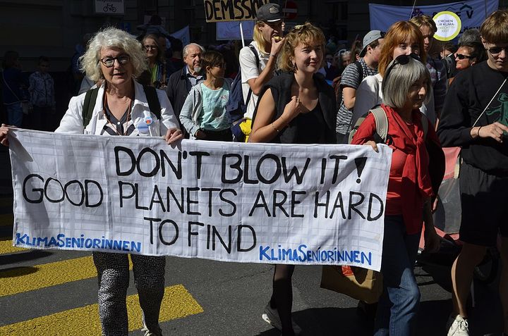 Bilden visar en klimatdemonstration. Demonstranter håller upp en vit banderoll.