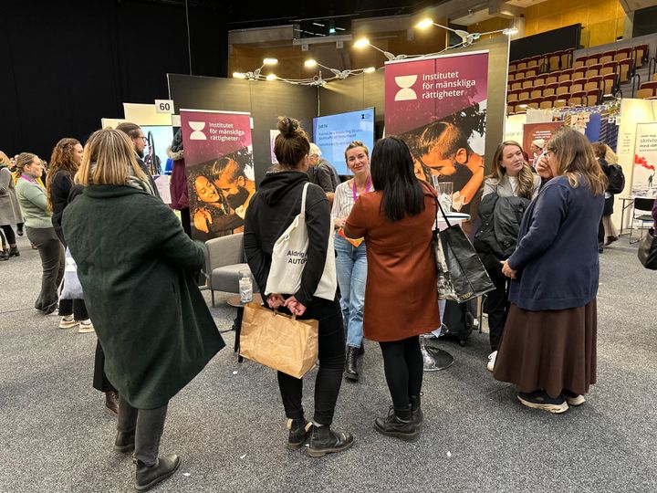 Människor står i en klunga runt institutets mässmonter på förra årets MR-dagar i Helsingborg. Fotografi.