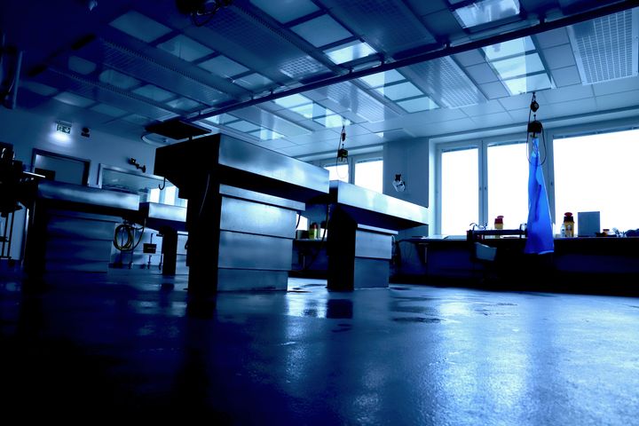 En mörk obduktionssal med metallbord och steril inredning.