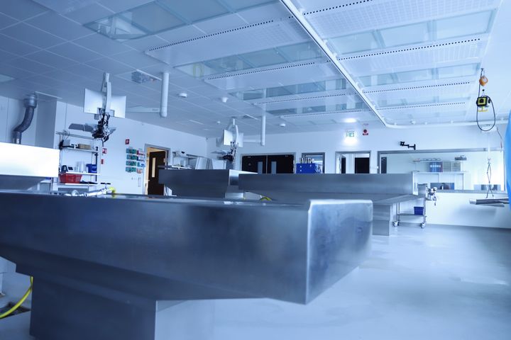 Obduktionssal med metallbord och medicinsk utrustning.