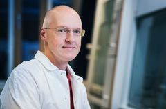 En man i vit skjorta sitter framför en dator