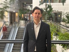 En man i kavaj står framför en rulltrappa