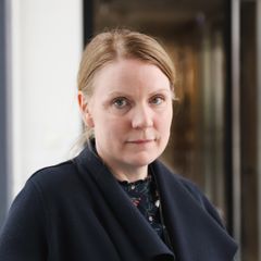 Porträtt av en kvinna i mörka kläder framför en dörr