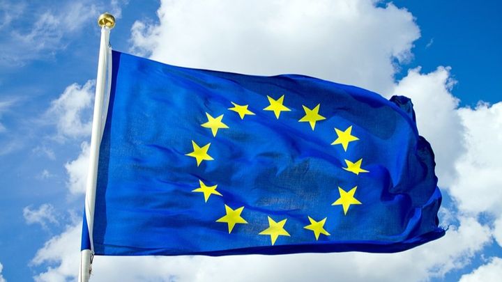 Den blåa EU-flaggan med gula stjärnor som vajar i vinden.