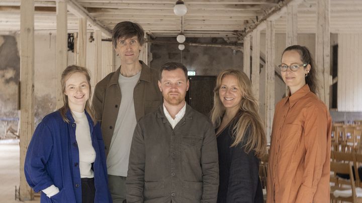 Fem personer står uppställda i en hantverkarmiljö.