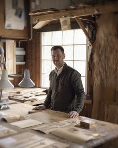 En man står inomhus bakom en arbetsbänk.