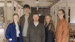 Fem personer står uppstllda i en hantverkarmiljö.