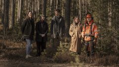 Fem personer står uppställda i en skog.