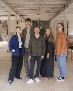 Fem personer står uppställda i en hantverksmiljö.